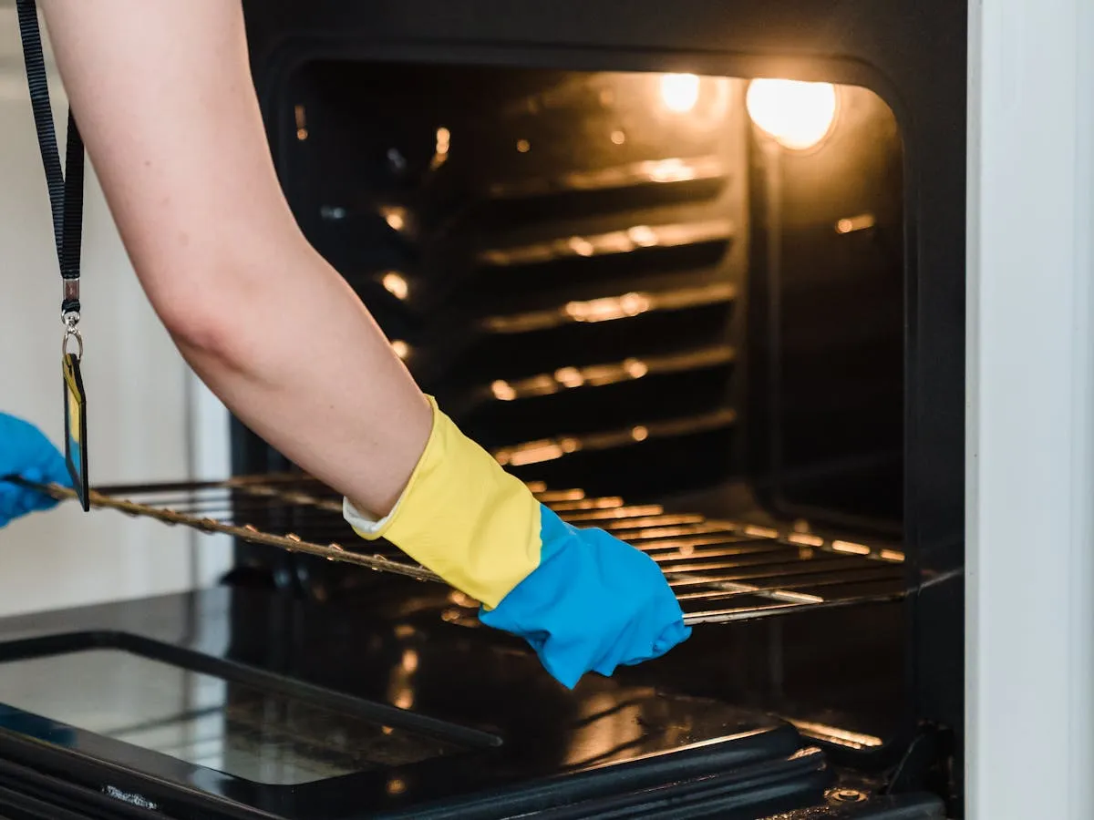 Gloved hands scrubbing the inside of an oven during a deep clean